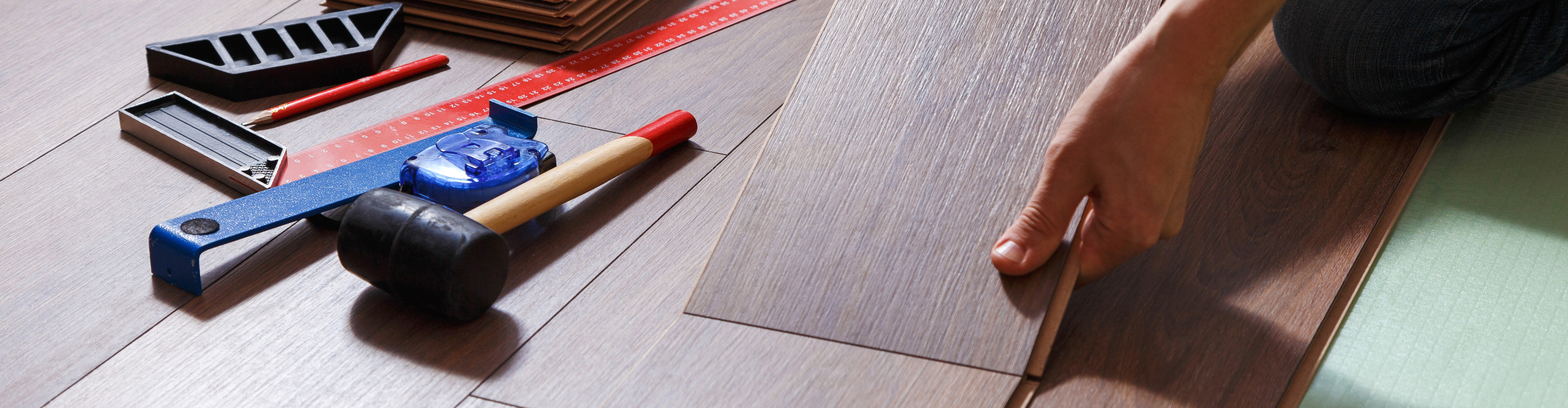 Close up of working hands with flooring and tools. 